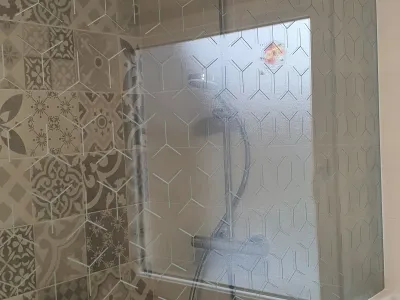 Salle de bain avec douche vitrée et carrelage aux motifs géométriques
