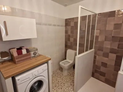 Salle de bain avec WC, meuble vasque en bois et miroir lumineux