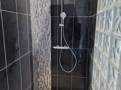 Douche avec carrelage gris et murs en verre